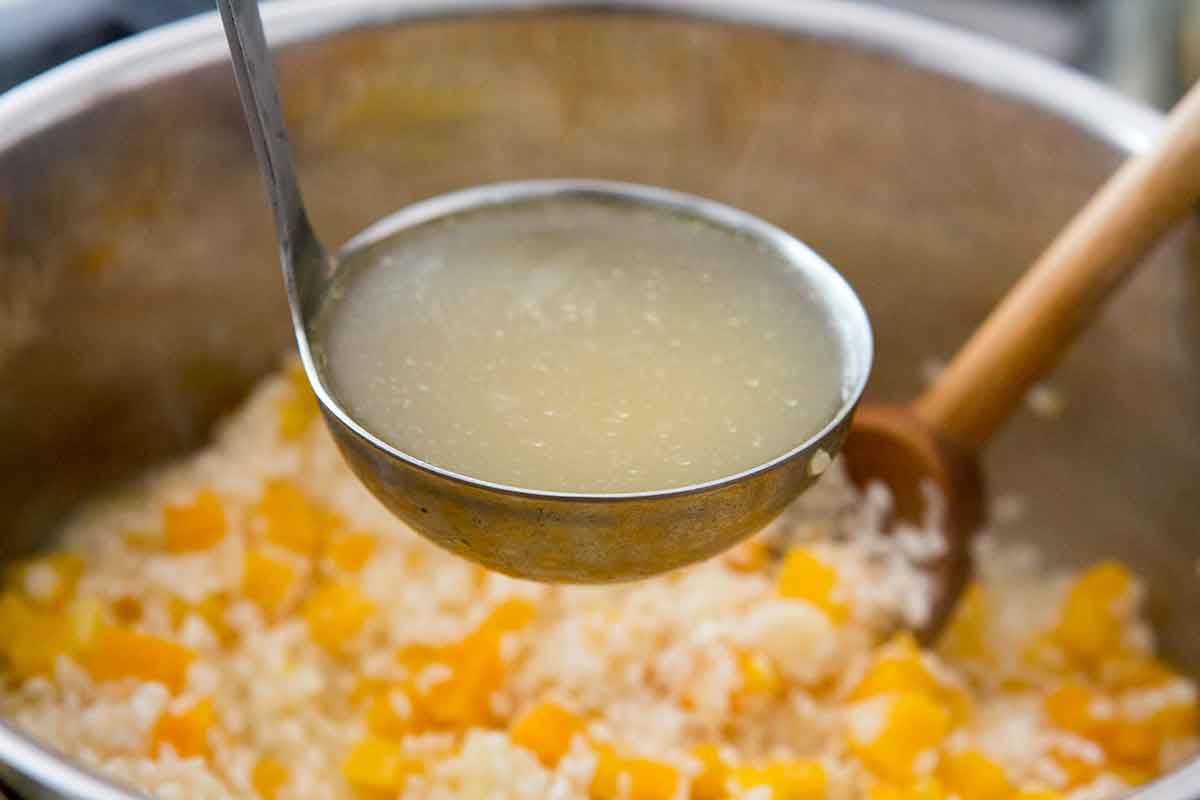 ladling broth into risotto