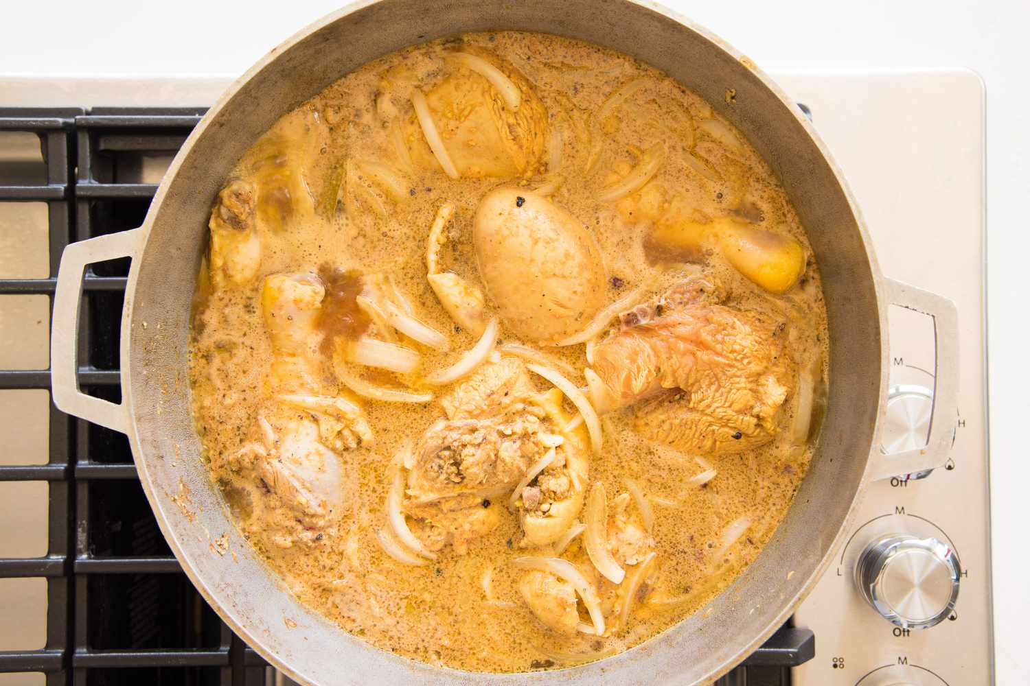 Seasoning, Onions, and Chicken Broth Added to Caldero for Pollo Guisado Recipe