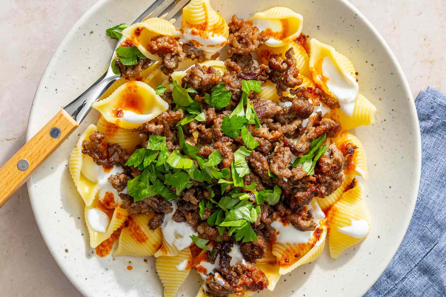Pasta dish with ground meat, yogurt sauce, and parsley