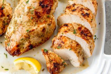 Cooked chicken breasts with a lemon wedge on a white plate