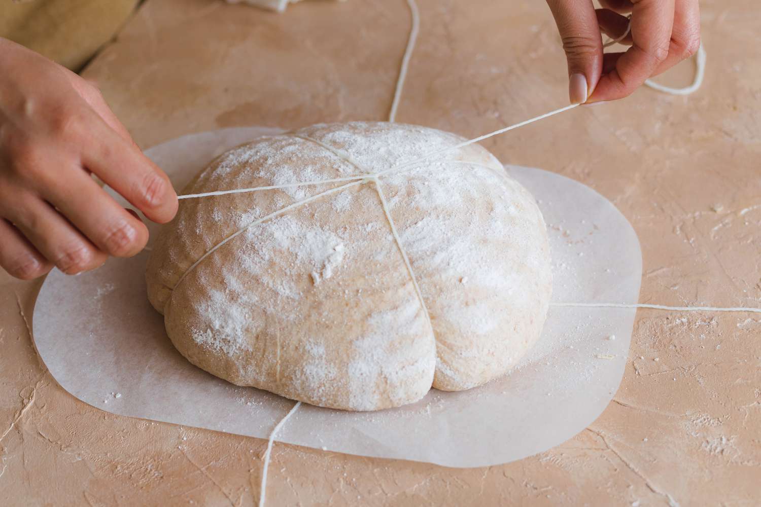 Tying dough with baking string to make a spiced sourdough bread shaped like a pumpkin.