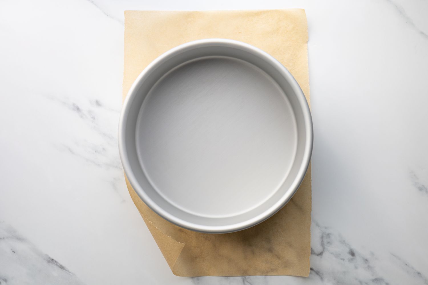 A round cake pan on tip of a piece of parchment paper