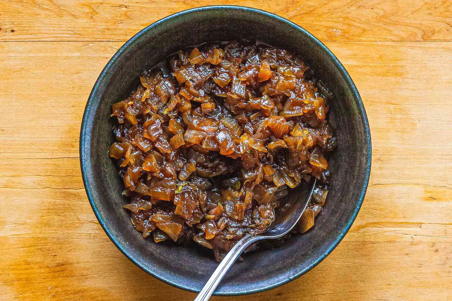 Balsamic onion jam in a grey bowl with a spoon.