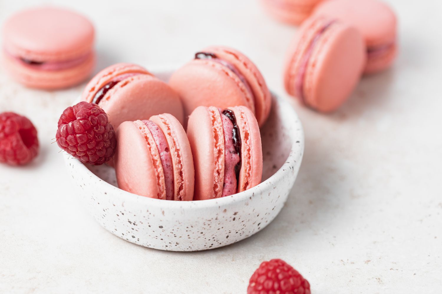 Raspberry macarons filled with raspberry buttercream in a small bowl.