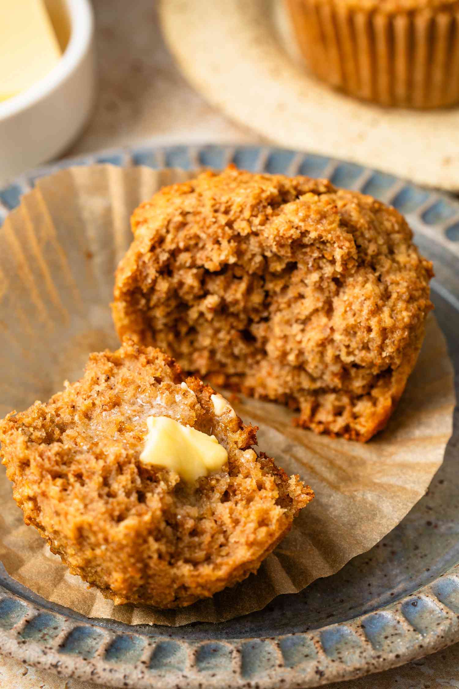 Halved bran muffin smeared with butter on a plate