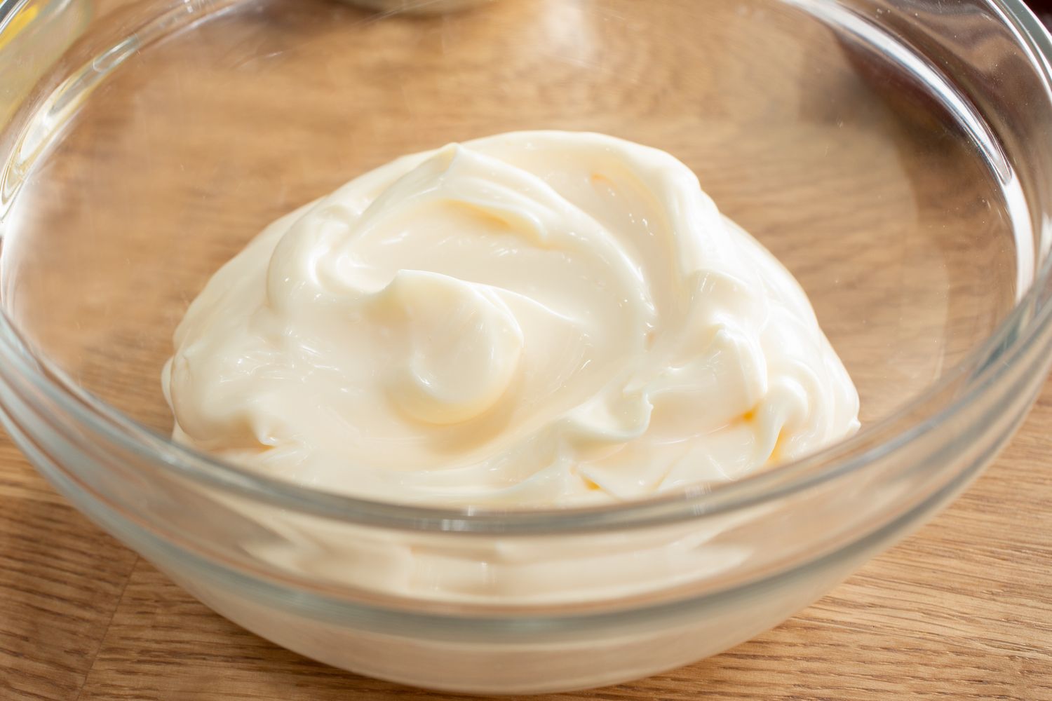 A bowl of mayonnaise on a wooden surface