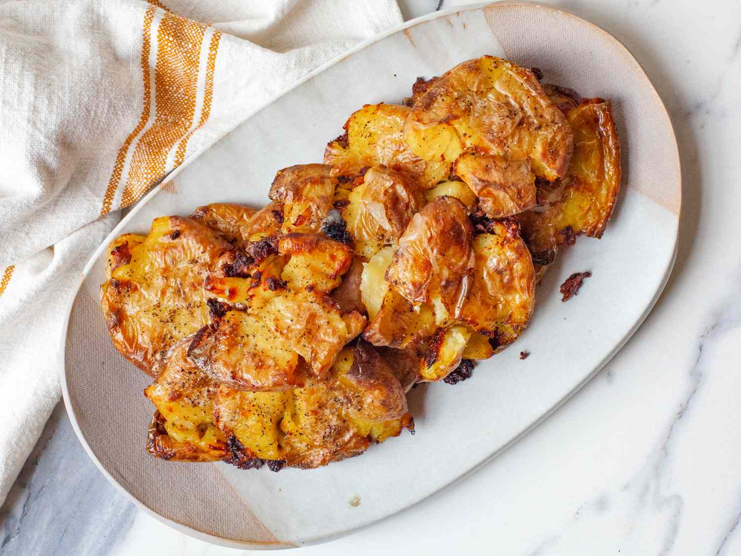 Smashed baked potatoes on a white serving plate