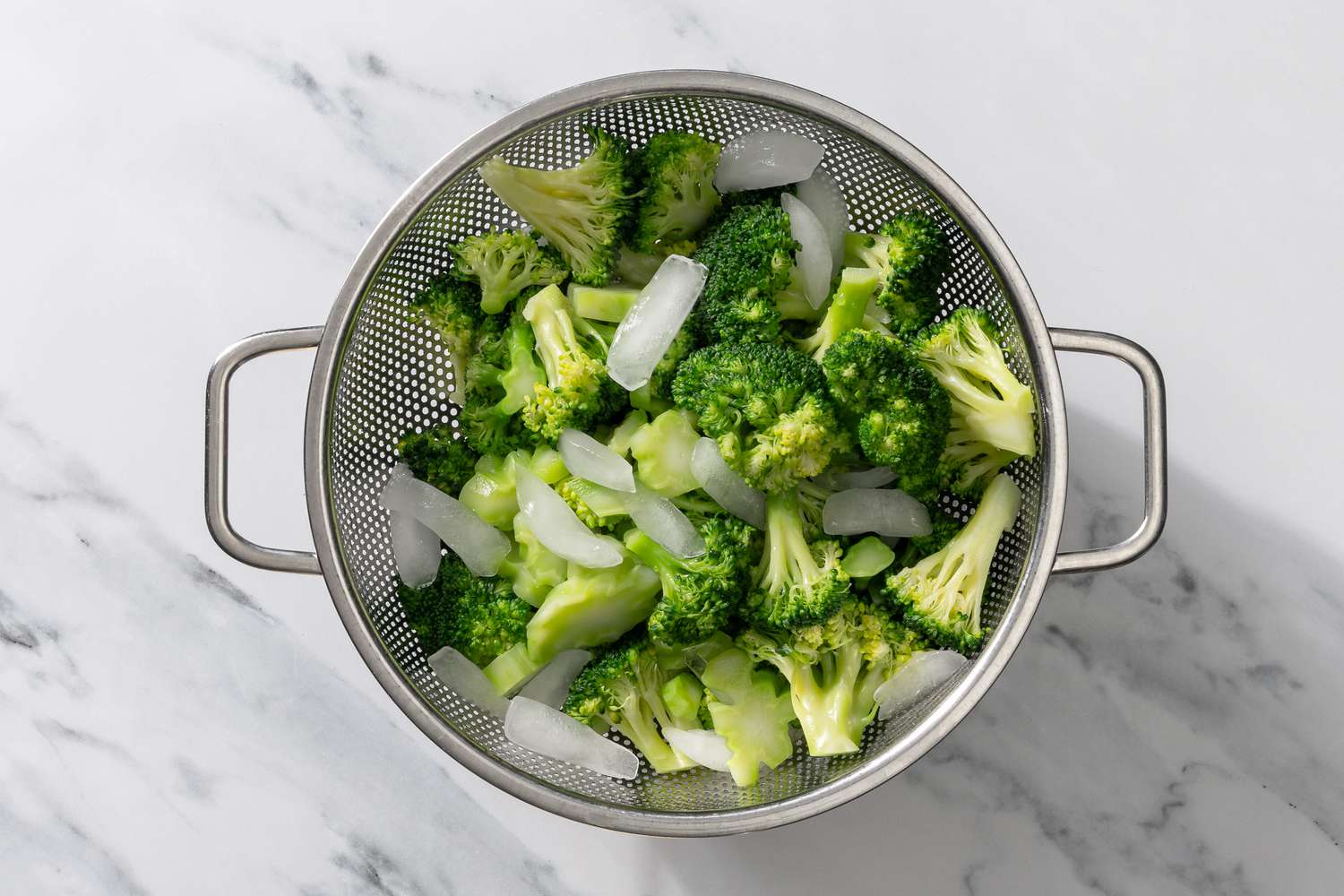 cooked broccoli florets in a strainer with ice cubes for My Mom’s Famous Broccoli Cheese Casserole