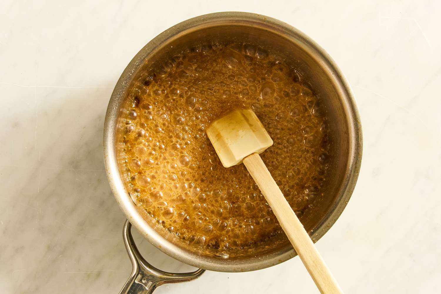 butter and brown sugar mixture bubbling in a saucepan with a spatula for Grandma’s Oatmeal Cake