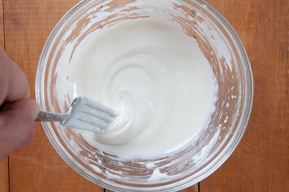 A fork is mixing the icing ingredients for the best King Cake.