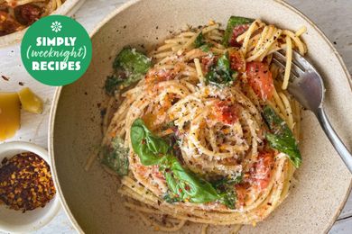 A bowl of pasta garnished with spinach and red pepper flakes, Simply Recipes logo in the corner