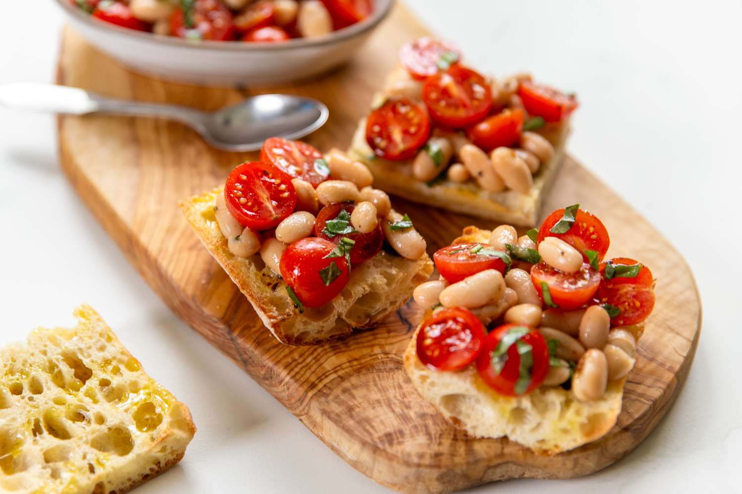 White bean and tomato bruschetta on a wooden cutting board