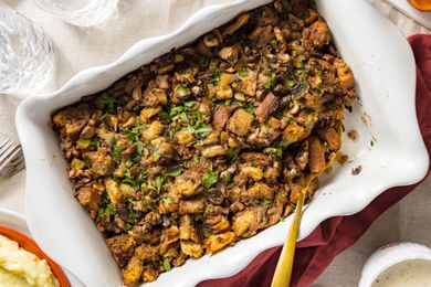 Table Setting: Vegan Mushroom Stuffing in a Casserole Dish Next to a Bowl of Mashed Potatoes, Two Glasses of Water, and a Table Napkin
