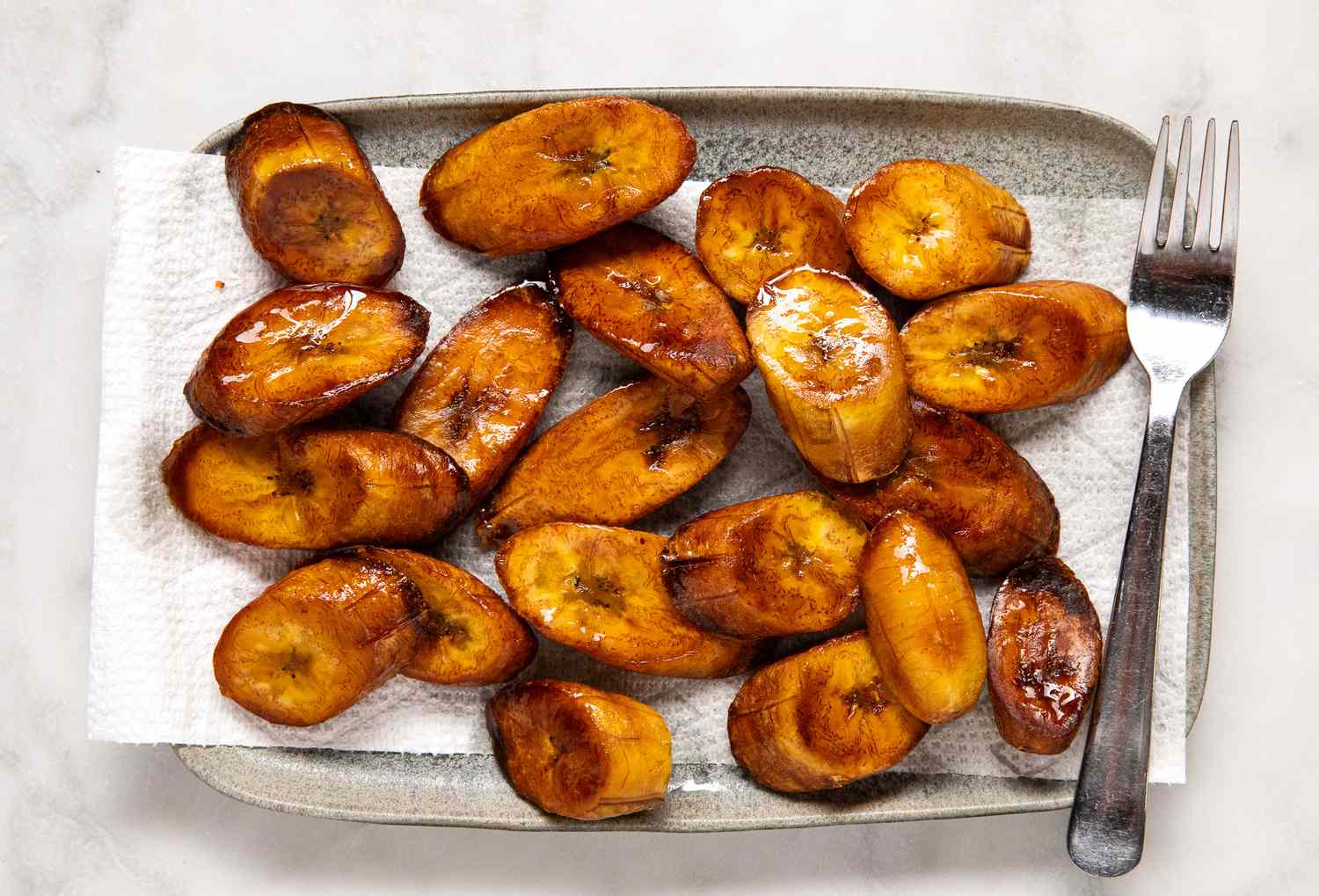 Fried Plantains on a Paper Towel Lined Plate With a Fork