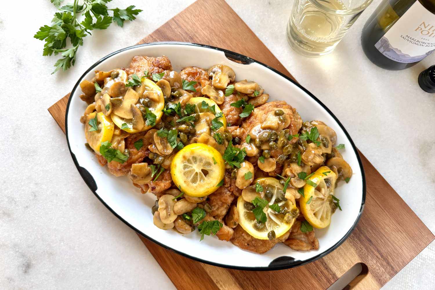 A plate of chicken piccata garnished with lemon slices, capers, and parsley