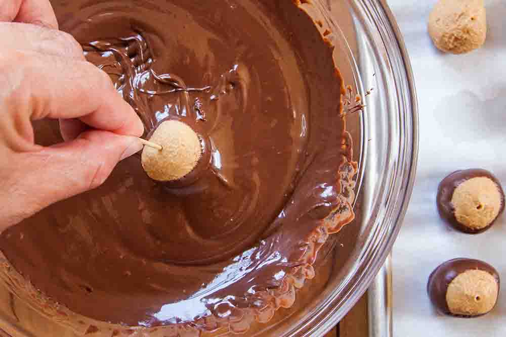 Coating buckeye balls with melted chocolate.