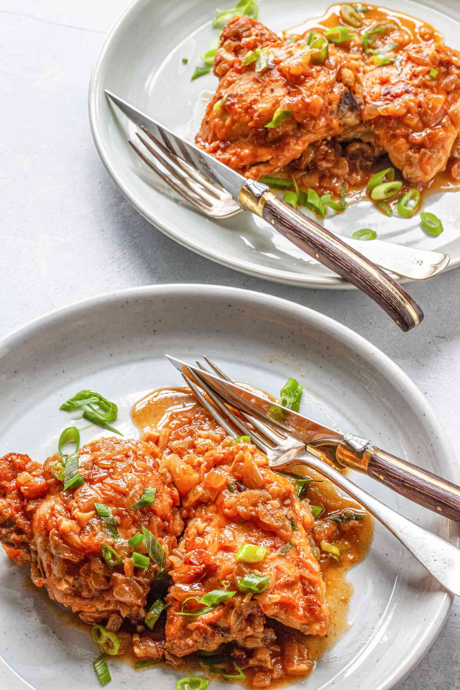 Comfort food classic: smothered chicken and gravy on two white plates with utensils.