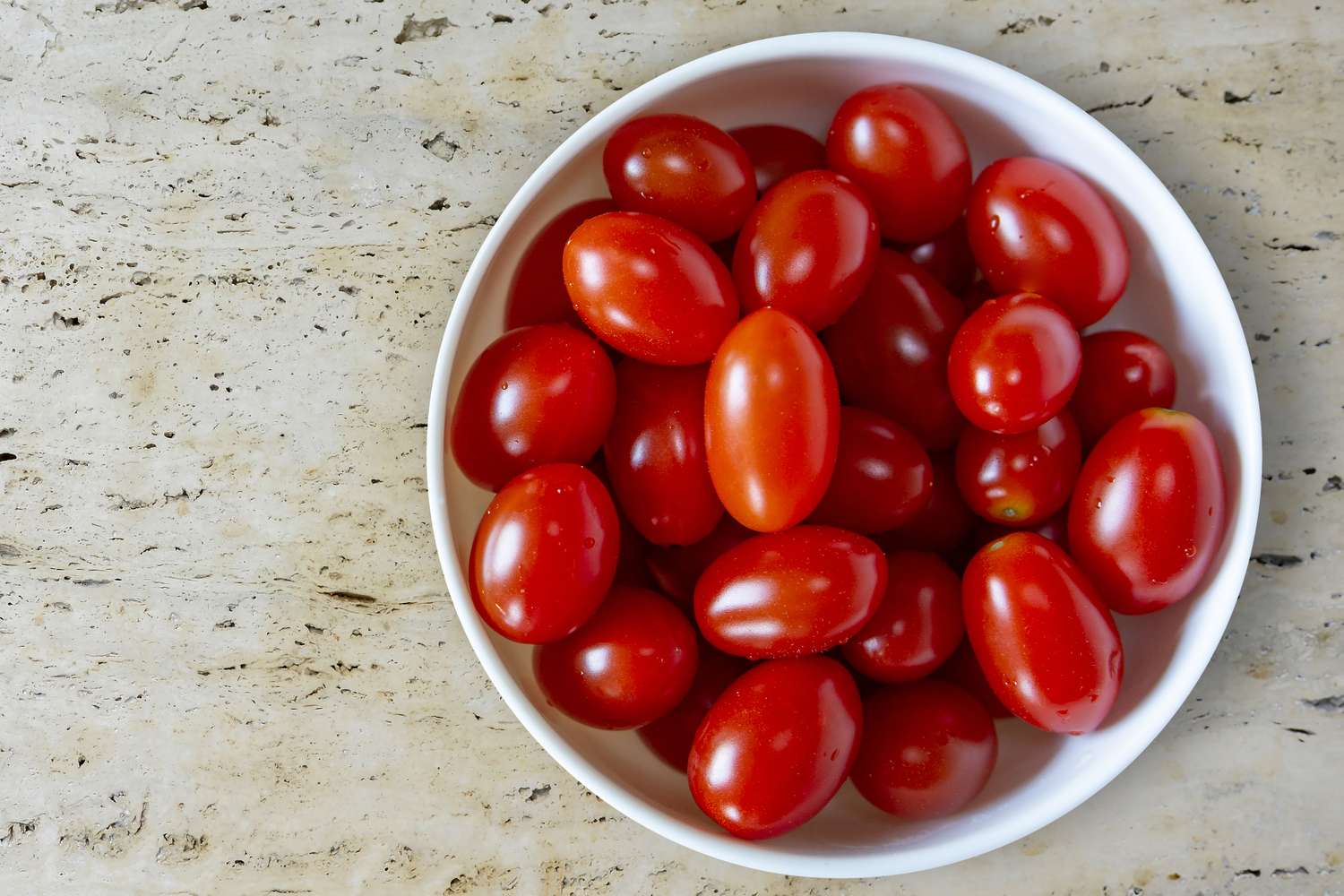 A bowl of small ovalshaped tomatoes on a countertop