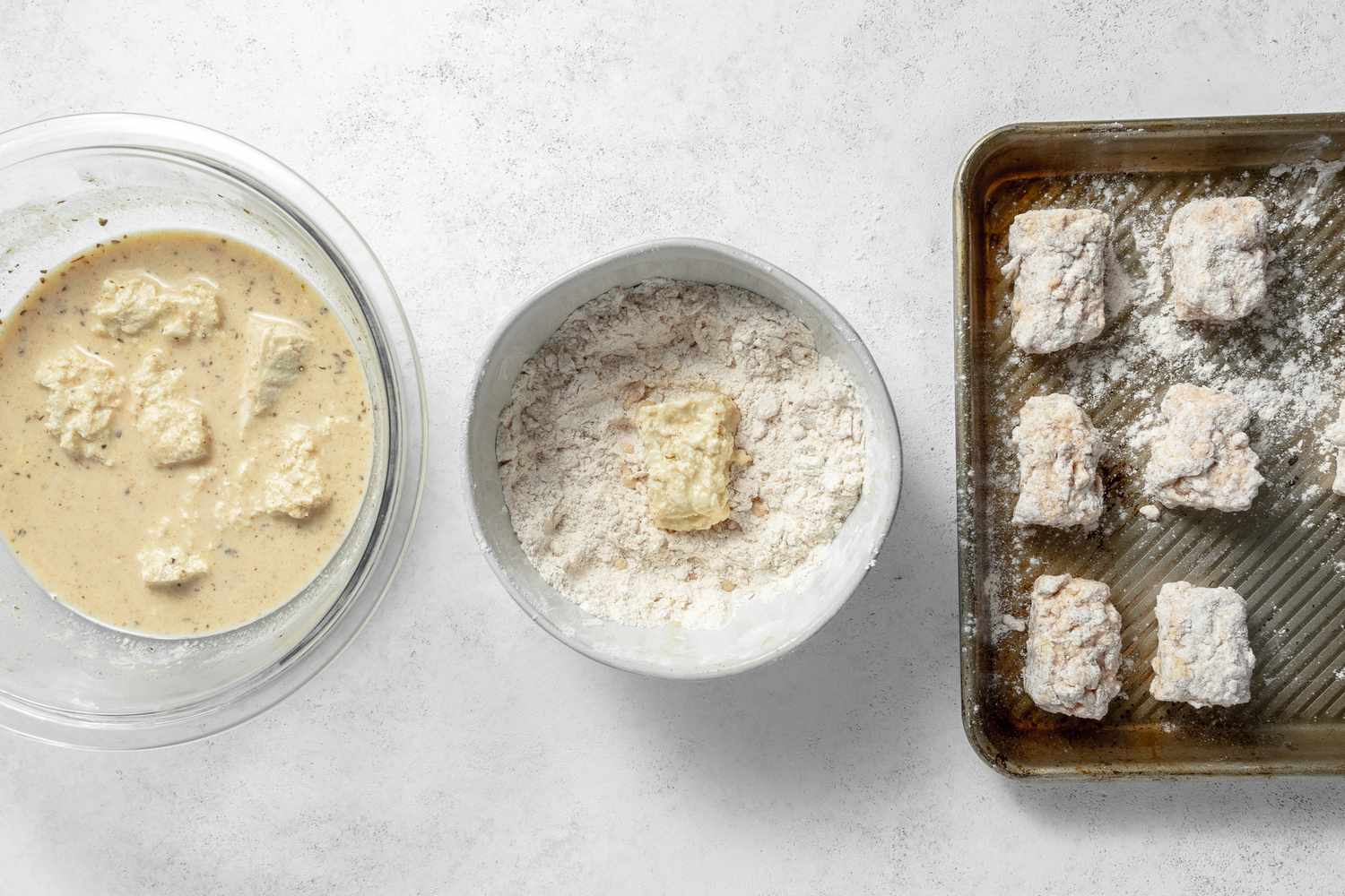 Dredging Station: Tofu Nuggets in a Bowl of Marinade, a Tofu Nugget in a Bowl of Flour, and Vegan Chicken Nuggets on a Baking Pan