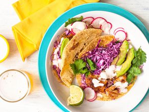 A plate of fish tacos with a glass of beer nearby