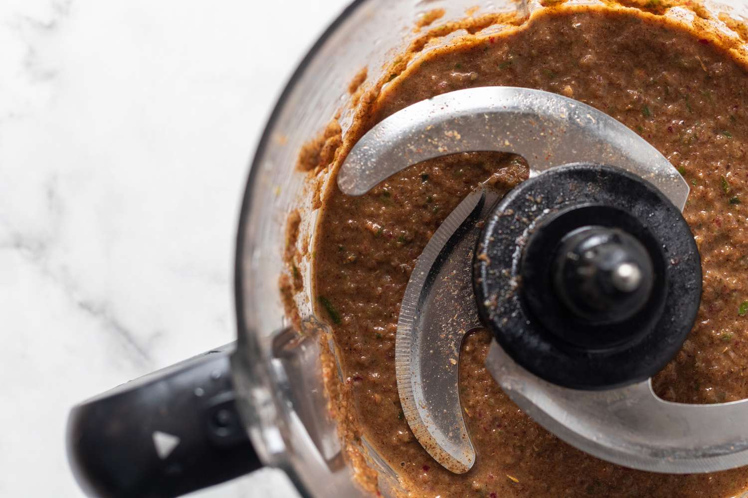 Overhead view of a food processor with jerk chicken marinade inside.