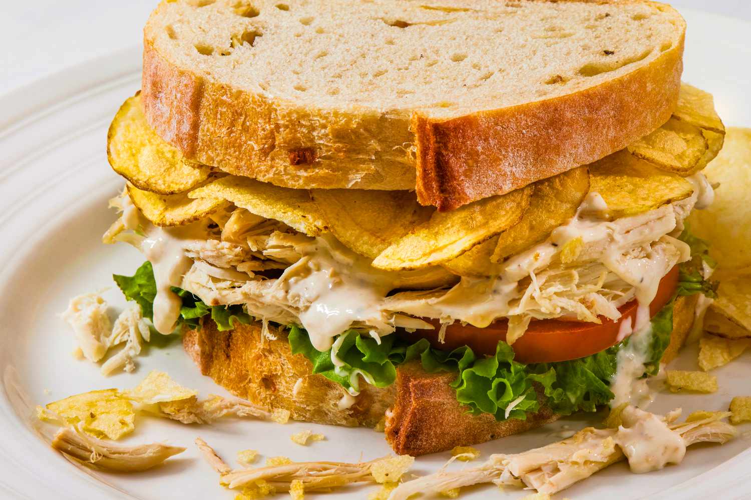 chicken salad sandwich with potato chips in the sandwich.