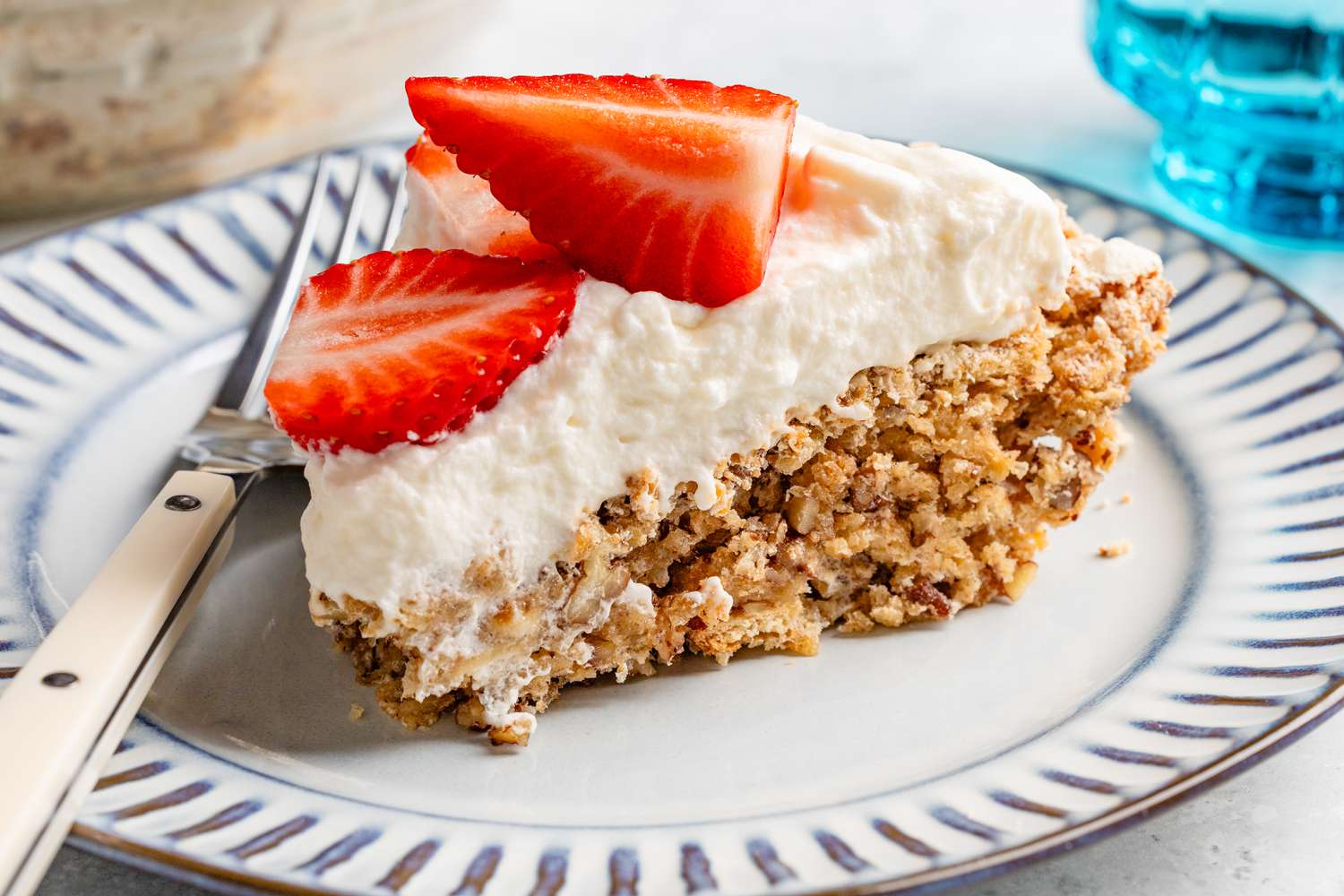 soda cracker pie slice (topped with whipped cream and fresh strawberries) on a small plate with a fork