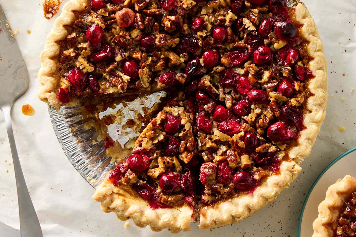 Cranberry pecan pie with a slice removed displayed in a pie dish