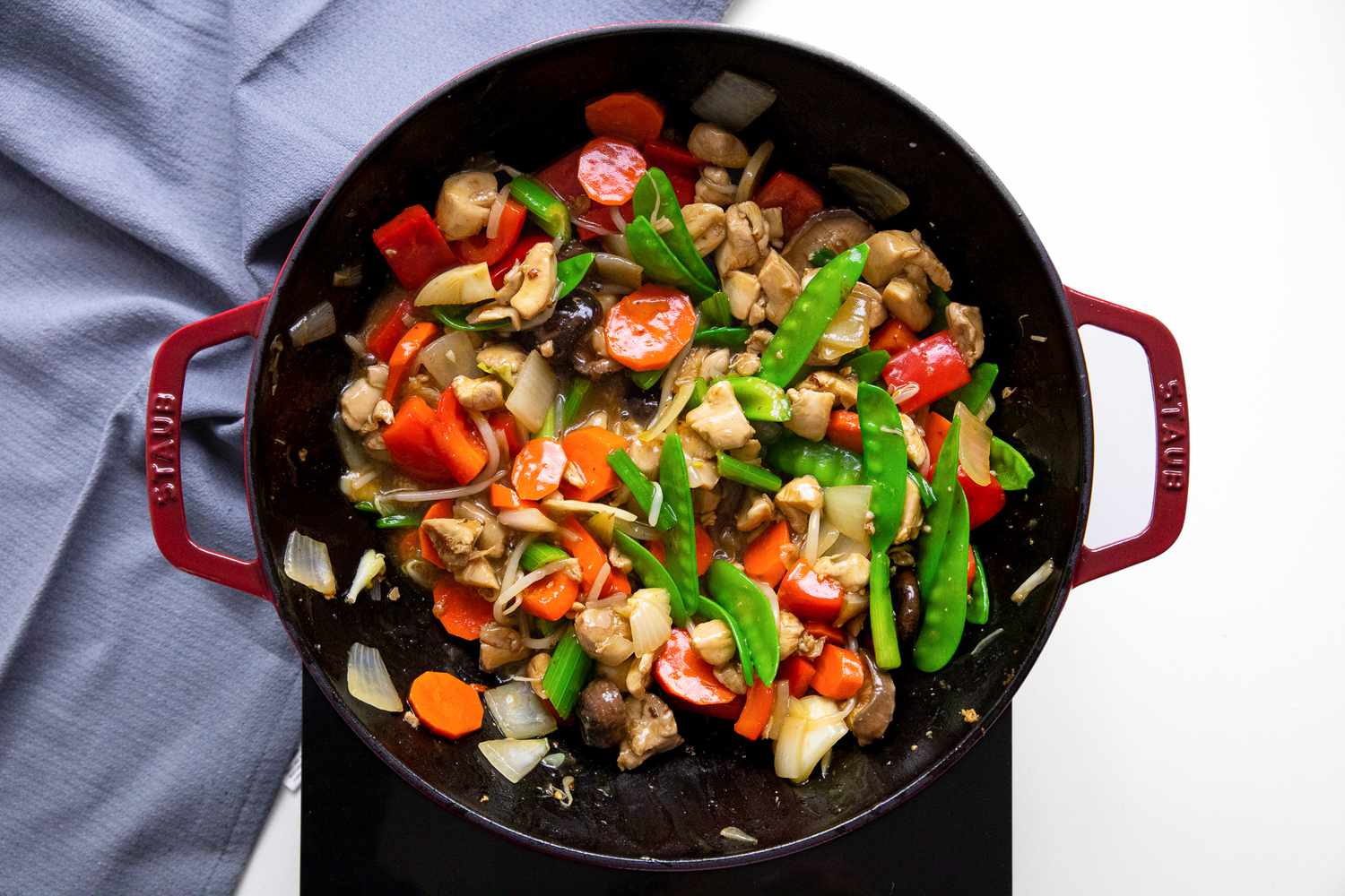 Chop Suey in a Wok on a Portable Burner Next to a Blue Kitchen Towel 