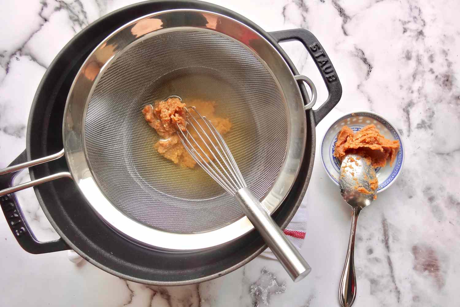 Whisking miso into broth to make miso soup.