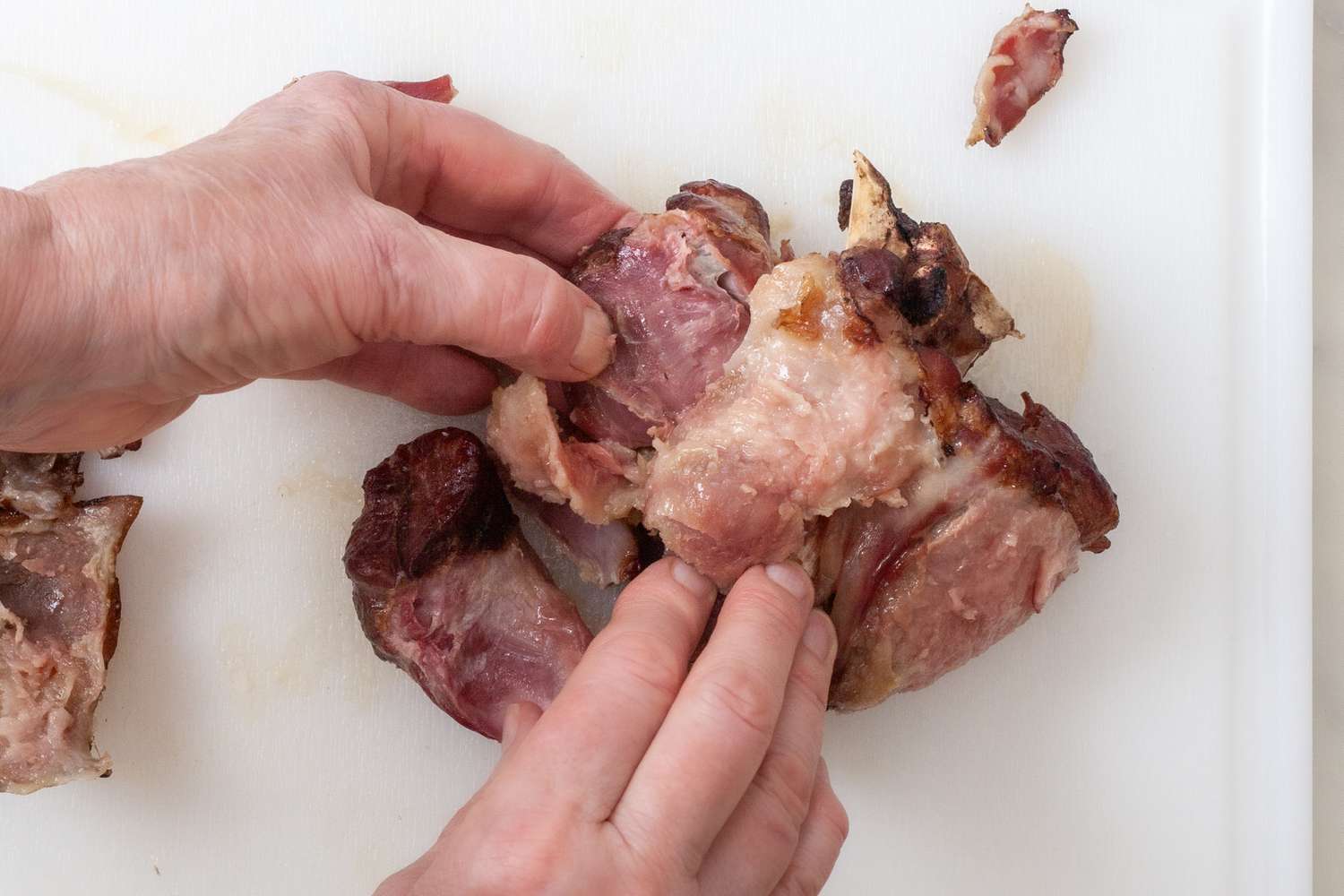 Pulling the meat off a ham hock for a southern collard greens recipe.