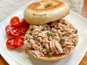 3-ingredient tuna salad on a toasted bagel on a plate with a serving of halved grape tomatoes