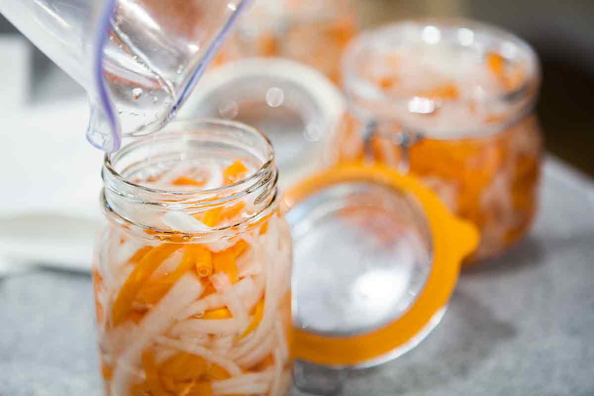 pouring pickling liquid over carrots and daikon for do chua vietnamese pickles