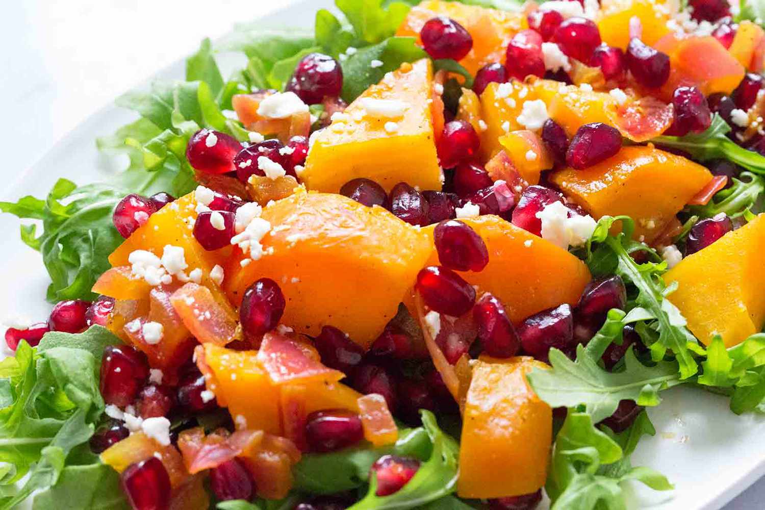 A platter of golden beet and pomegranate salad over baby arugula