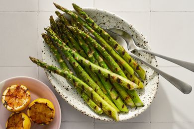 Platter of grilled asparagus with small plate of grilled lemons