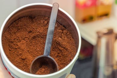 Ground coffee in a jar with a coffee scoop