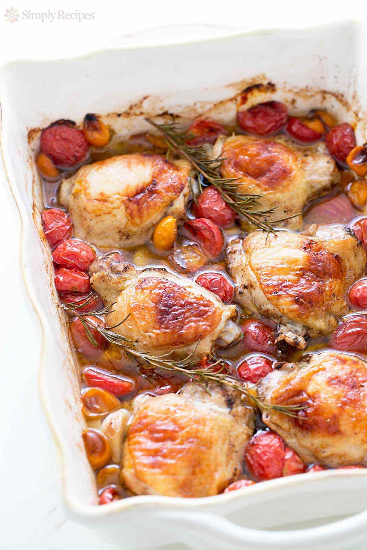 Baked chicken thighs with cherry tomatoes in a white baking dish