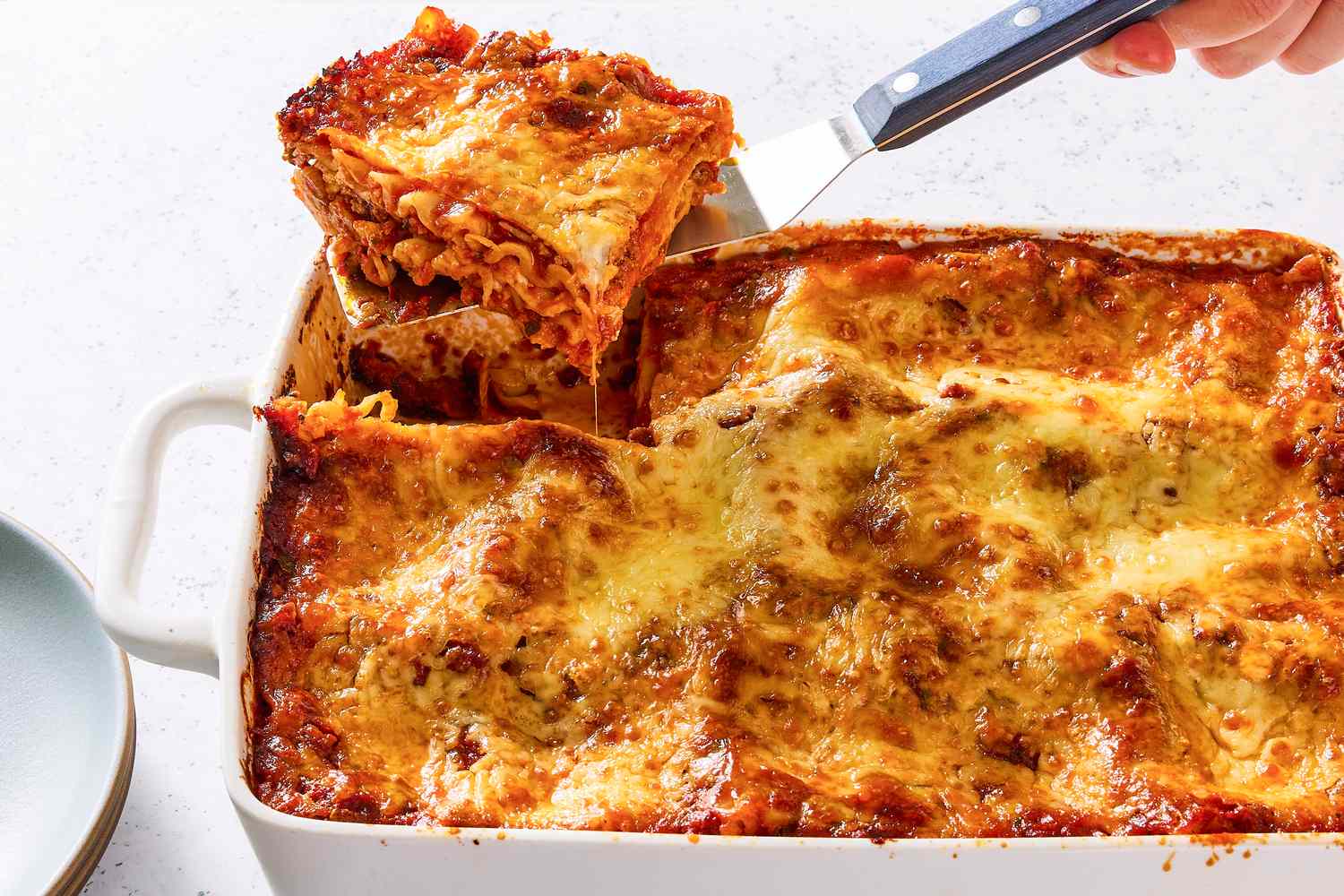 A slice of homemade lasagna being served from a casserole dish