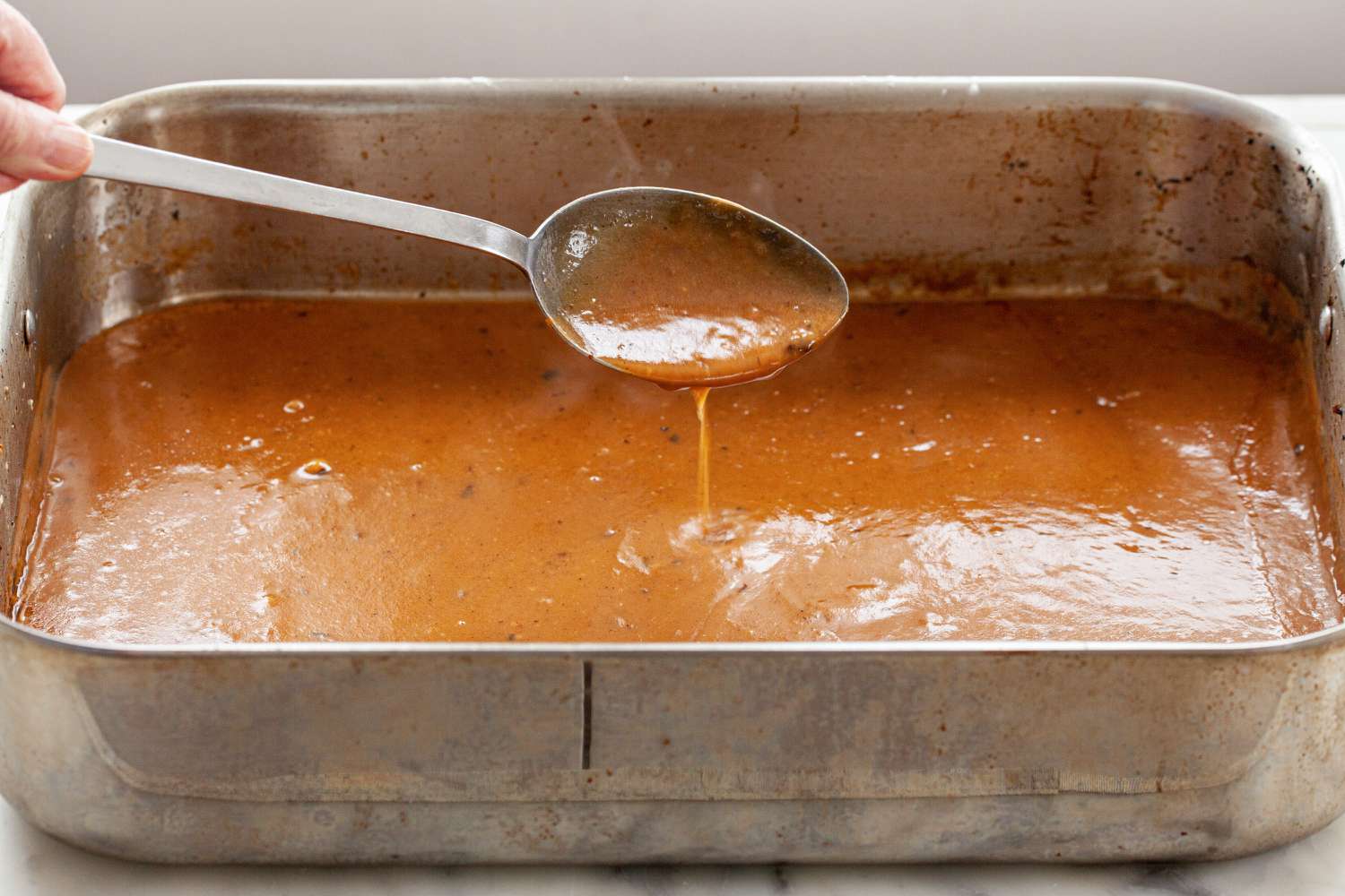 Gravy in the bottom of a roasting pan to make Rosemary and Thyme Prime Rib.