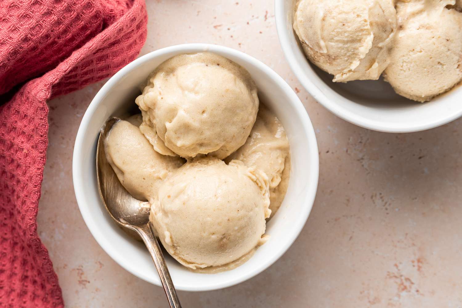 Scoops of Banana Nice Cream in a Bowl With a Spoon, and Next to It, Another Bowl of Nice Cream and a Kitchen Towel