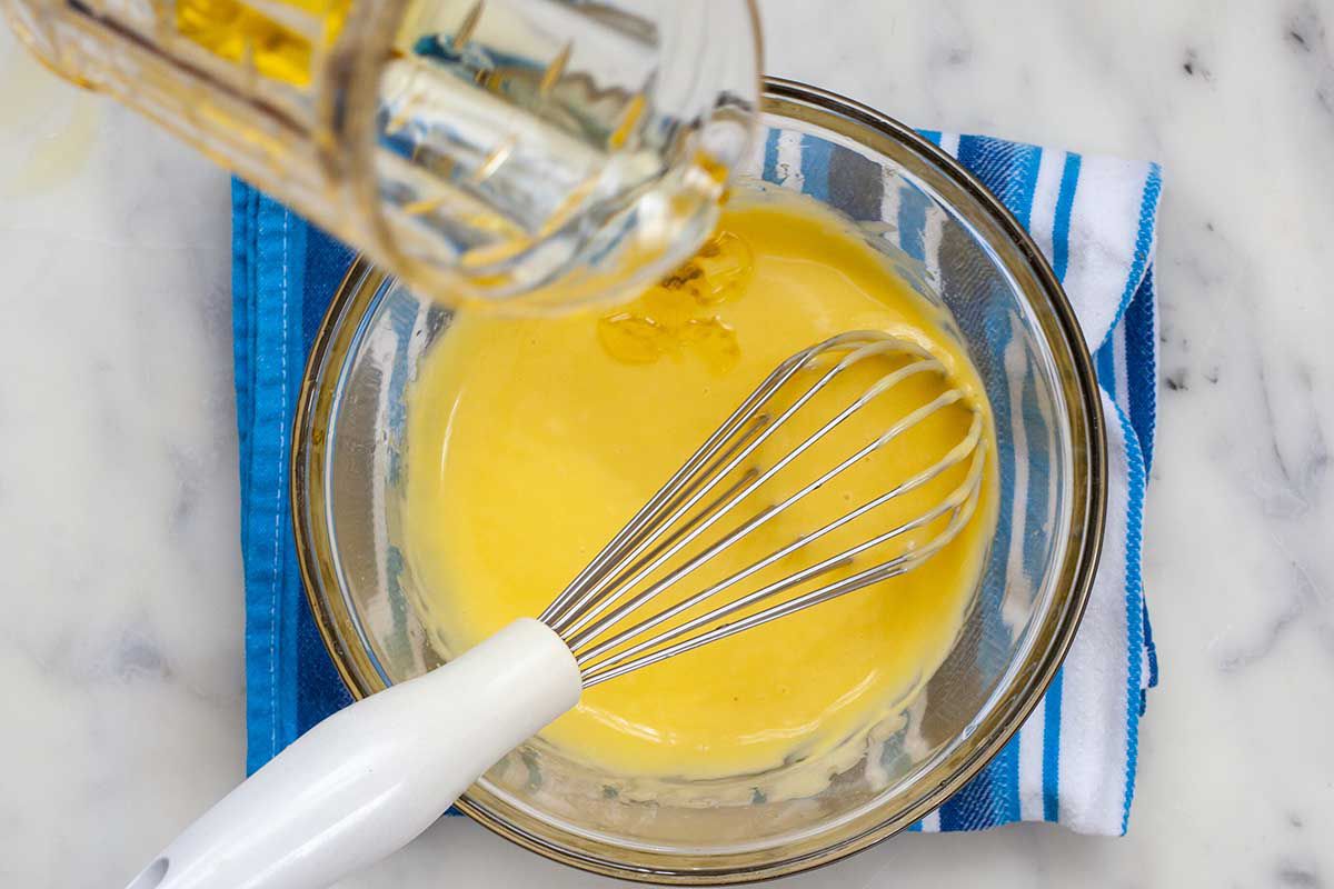 Oil is being whisked into a bowl to show how to make garlic aioli recipe.