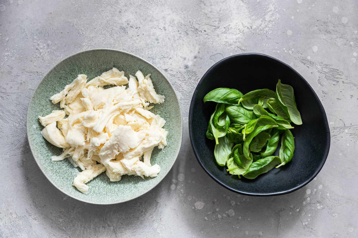 Bowl of Fresh Mozzarella Shredded Into Bite Size Pieces and a Bowl of Fresh Basil Leaves for French Bread Pizza Recipe
