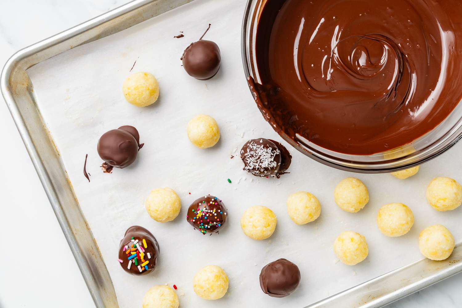 Potato candy truffles dipped in chocolate, placed on a parchment paper-lined baking sheet, and topped with various toppings (sprinkles, shredded coconut, etc)