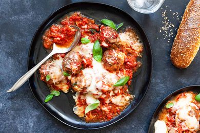 Mozzarella-stuffed meatballs with sauce on a plate with a spoon and bread on the side
