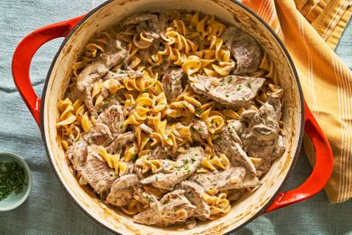 A Dutch oven full of beef stroganoff over corkscrew pasta
