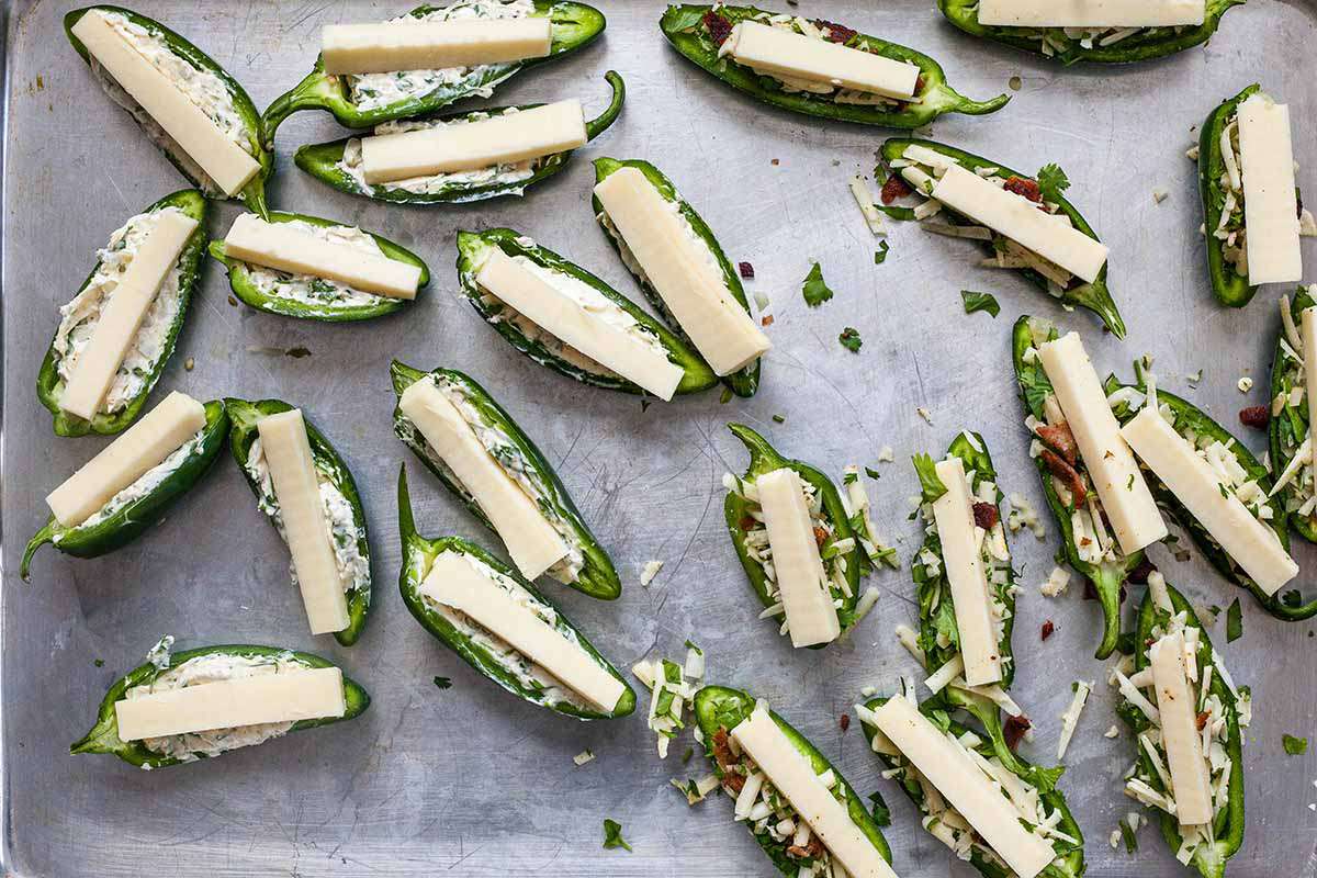 Uncooked cheese and bacon Stuffed Jalapeños on a baking sheet