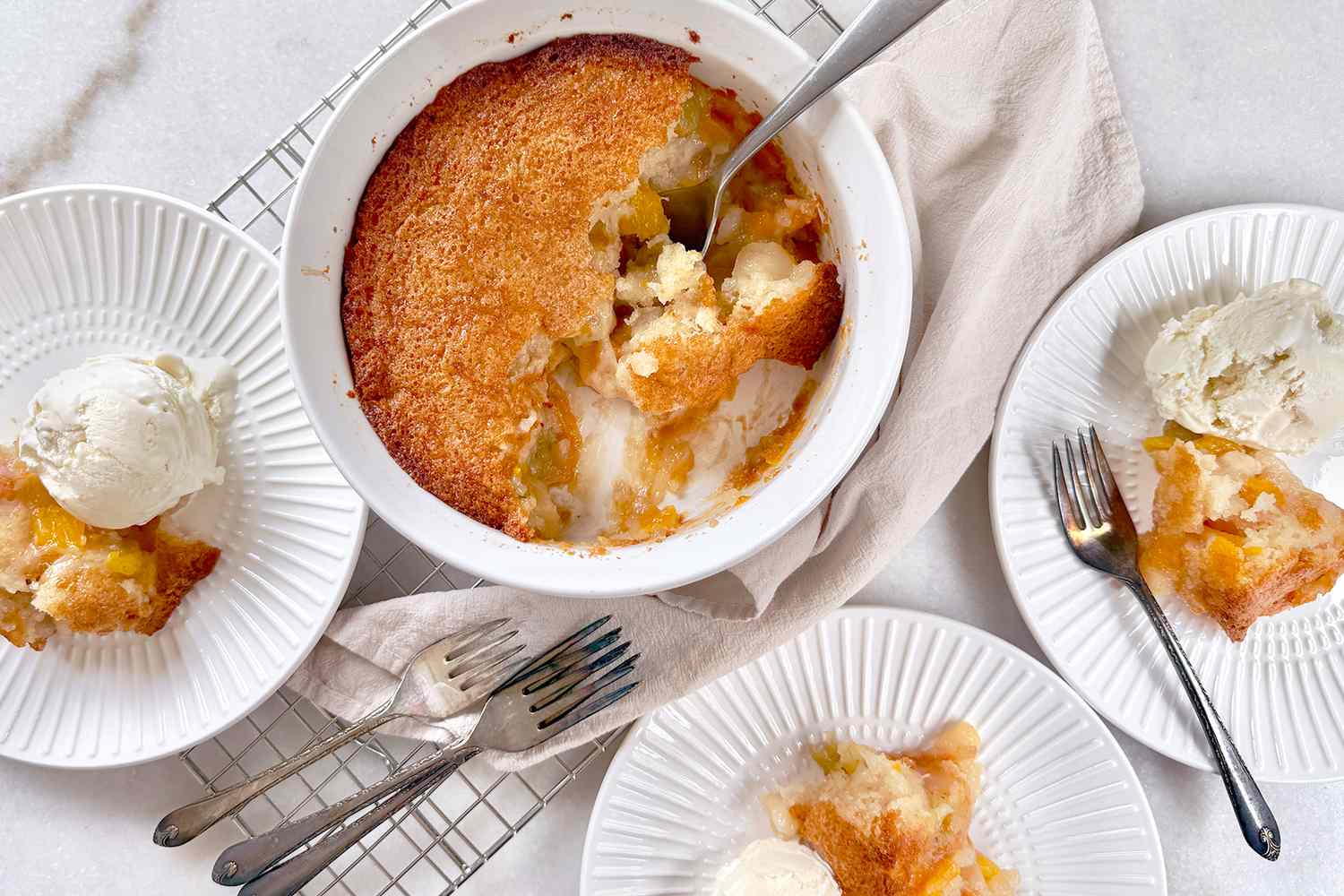 A baked fruit cobbler dessert served with vanilla ice cream on separate plates