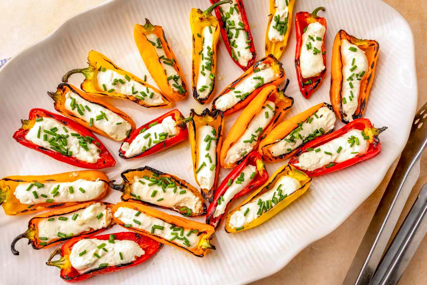 Grilled peppers stuffed with feta cheese and garnished with chives on a serving plate