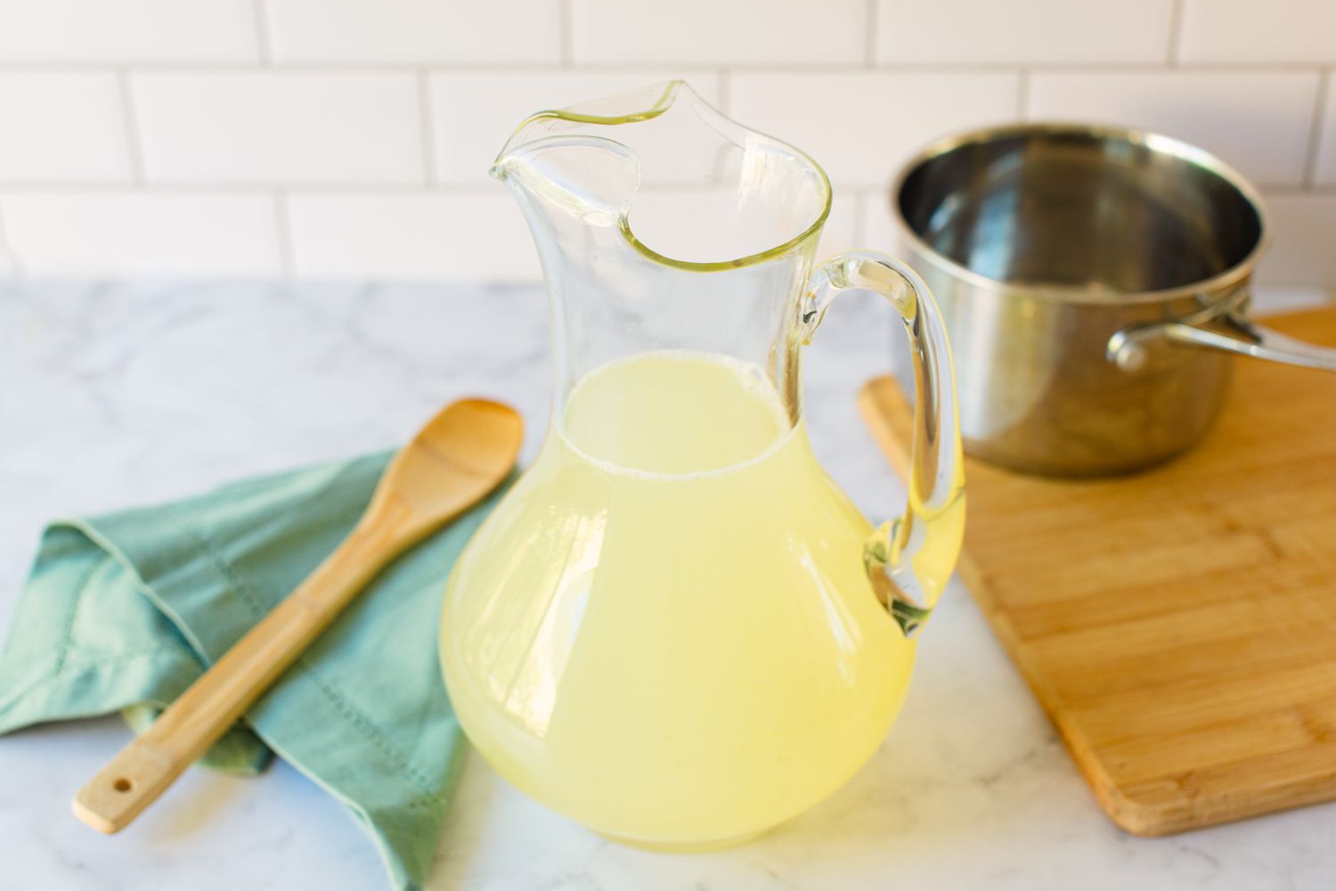 Mixing simple syrup, water, and lemon juice to make a lemonade recipe