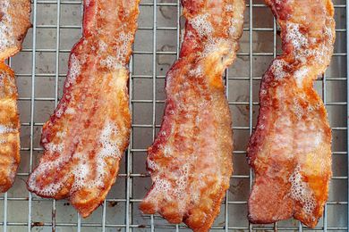 Four slices of oven baked bacon on a cooling rack.